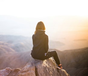 person-sitting-on-top-of-gray-rock-overlooking-mountain-during-daytime.jpg person sitting on top of gray rock overlooking mountain during daytime